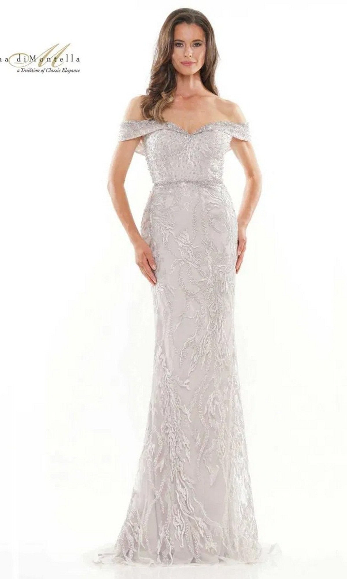 A woman stands against a plain white background, wearing the Rina Di Montella RD2713 long formal dress in nude, featuring intricate embroidery and an off-the-shoulder design.
